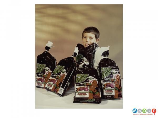 Scanned image showing a boy with several multi-packs of crisps.