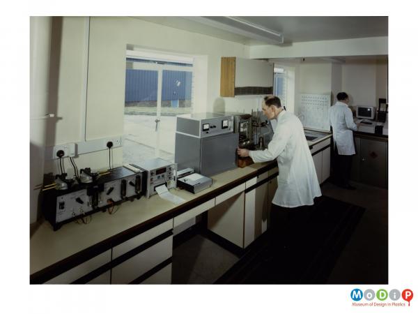 Scanned image showing two men wearing white coats in a laboratory.