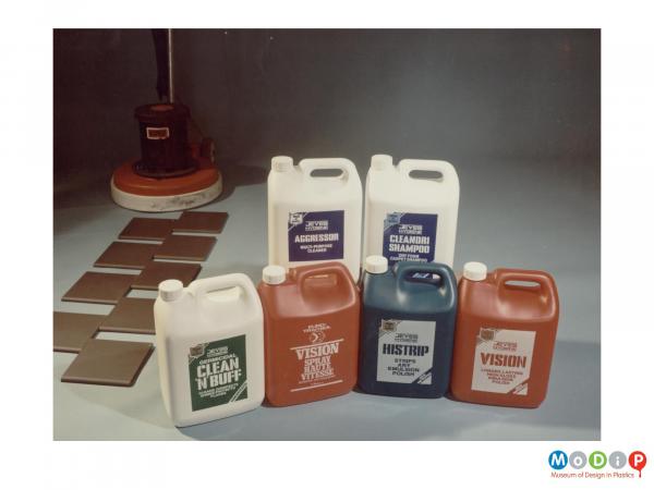 Scanned image showing a range of 6 cleaning product bottles with a floor polisher in the background.