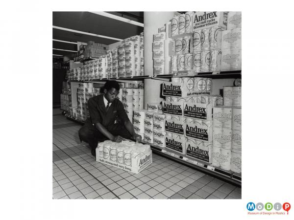 Scanned image showing shrink wrapped toilet rolls in a retail setting.