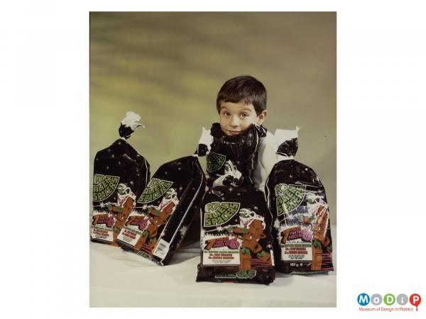 Scanned image showing a boy surrounded by 5 multi packs of crisps.