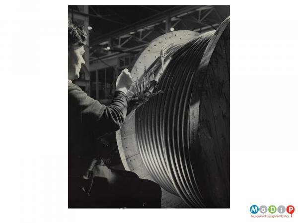 Scanned image showing an employee manipulating cable inside insulating tubes.