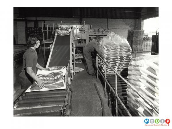 Scanned image showing male workers at an animal feed packing facility.