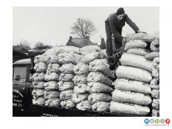 Scanned image showing sacks of coal piled on the back of a truck.