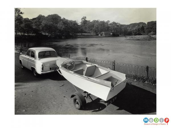 Scanned image showing small boat hitched to a car.