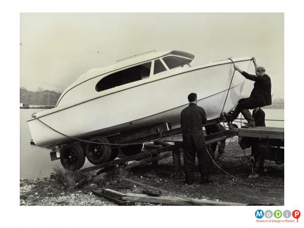 Scanned image showing a boat being launched from the back of a lorry.