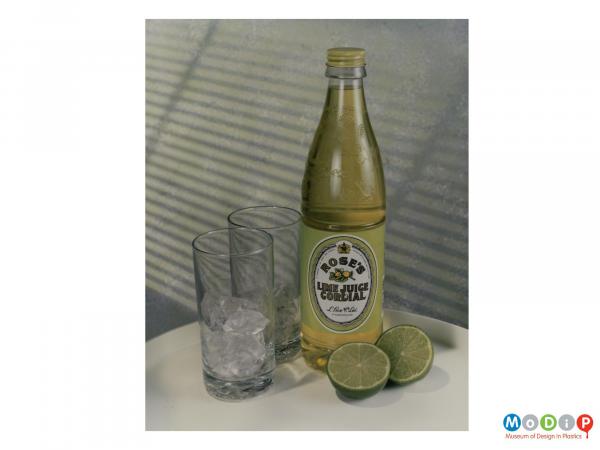 Scanned image showing a cordial bottle alongside 2 glasses and 2 lime halves.