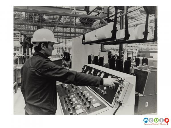 Scanned image showing a man at a control panel.