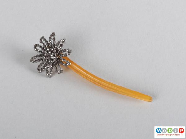 Top view of a hairpin showing the floral embellishment and two teeth.