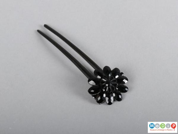 Top view of a hairpin showing the floral embellishment and two teeth.
