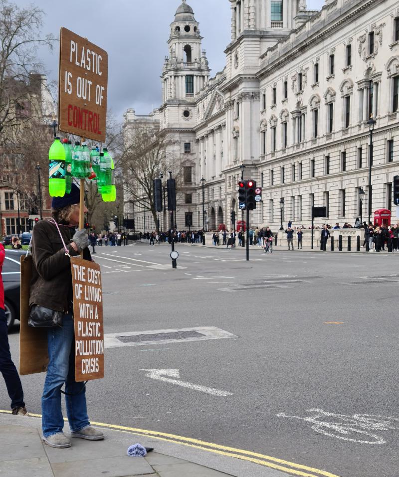 A protestor holding a placard and wearing a sandwich board.  