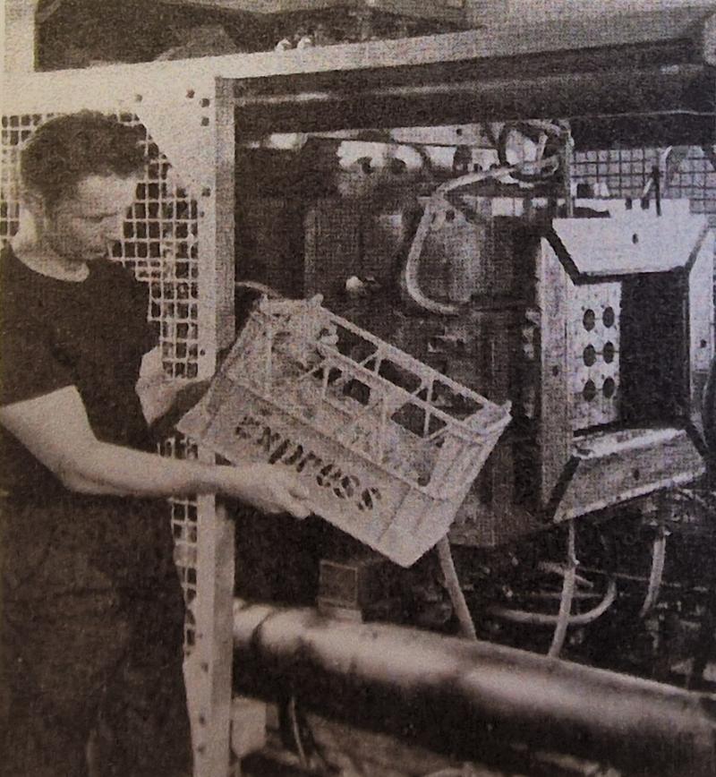 An operator of the Peco 60MR machine inspecting details of an Express Dairy plastic crate. 