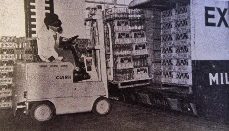 Plastic and Wire crates filled with Express Dairy bottles are loaded into a delivery truck. 